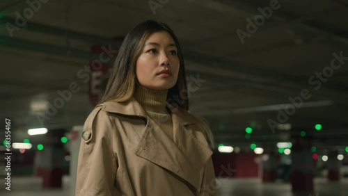 Moving shot female portrait confident Asian woman businesswoman driver engineer builder contractor architect pensive ethnic korean chinese japanese alone girl lady client wait taxi car in parking lot photo