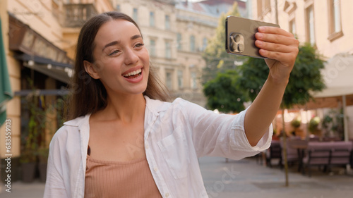 Caucasian joyful woman walking city center attractions street outside talking video chat chatting phone call smartphone vlog tourism travel looking at camera online smiling girl distant vacations trip