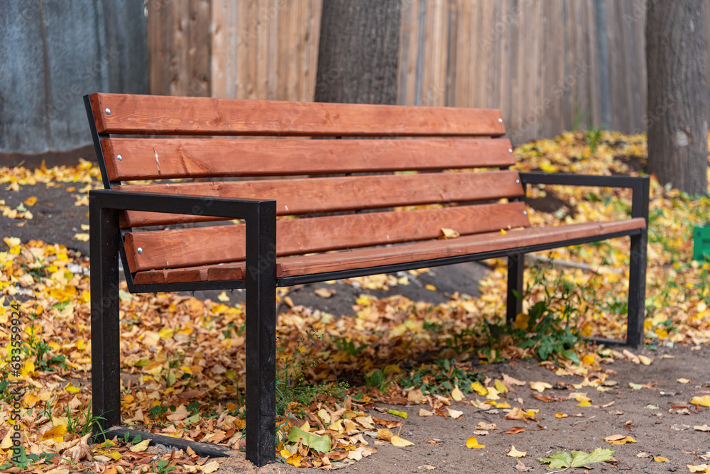 Modern wooden bench with fallen leaves on the ground. Modern wooden bench with fallen leaves on the ground.