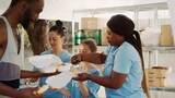 Female volunteers of different ethnicities provide homeless people with fresh fruit and free meals. Volunteering at food drive, caucasian and african american ladies help the needy and less fortunate.