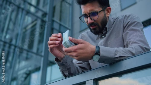 Indian Arabian upset poor man counting money cash calculate earnings income profit worried male businessman in city outdoors count dollars miserable salary problem financial crisis business inflation