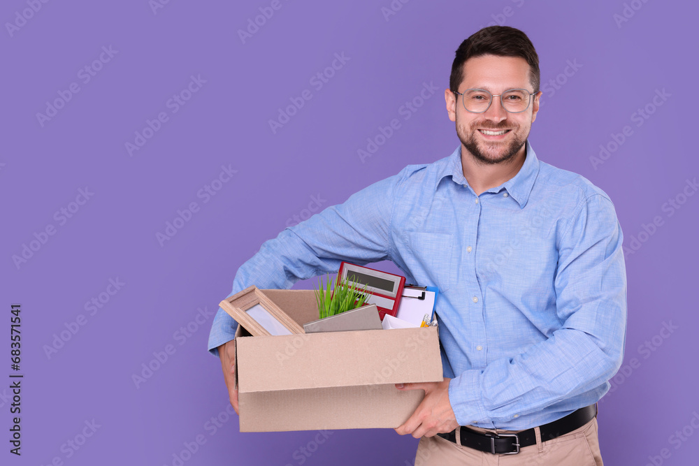 Happy unemployed man with box of personal office belongings on purple background. Space for text Happy unemployed man with box of personal office belongings on purple background. Space for text