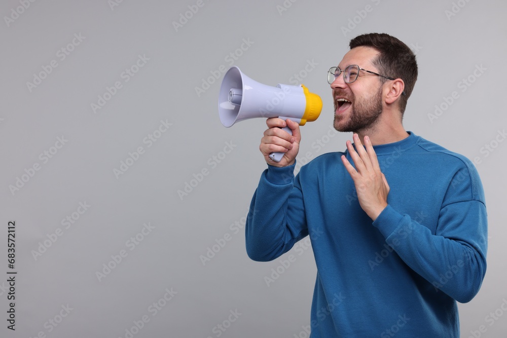 Special promotion. Man shouting in megaphone on light grey background. Space for text Special promotion. Man shouting in megaphone on light grey background. Space for text
