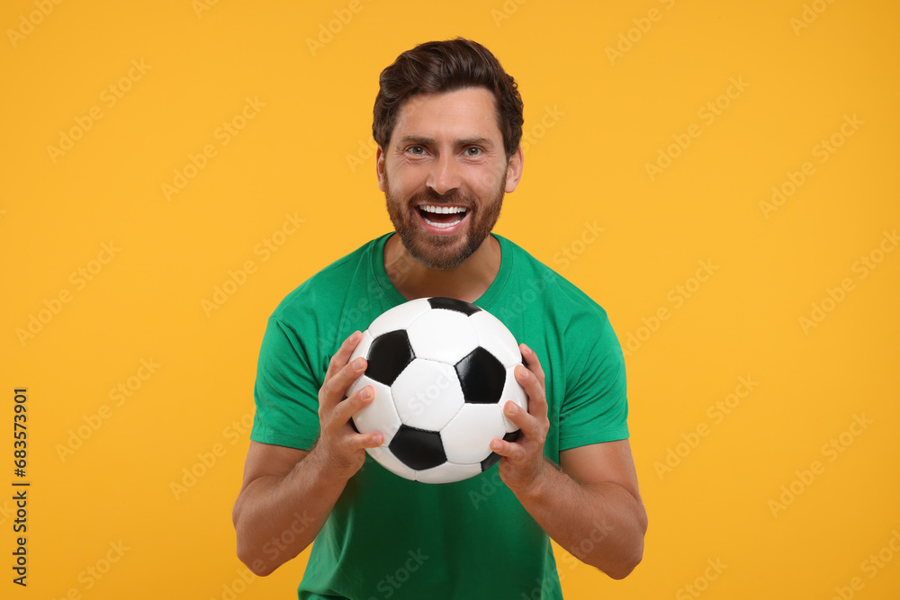Emotional sports fan with soccer ball on orange background Emotional sports fan with soccer ball on orange background