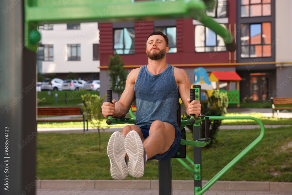 Fototapeta premium Man doing leg rise exercise at outdoor gym
