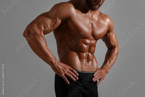 Young bodybuilder with muscular body on grey background, closeup