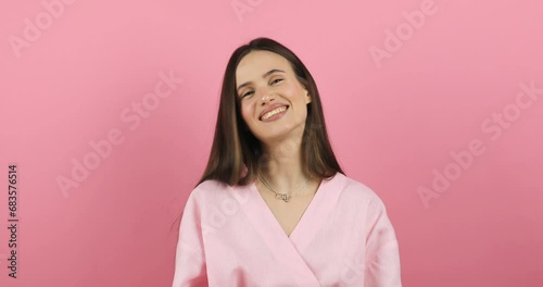 Portrait of young sexy playful brunette girl wear pink dress posing looking camera chewing bubble gum and pulling it out of teeth with fingers isolated on pink wall background in studio. photo