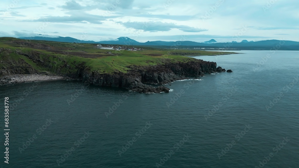 Top view of rocky coast on background of mountains on cloudy day. Clip. Beautiful northern landscape with rocky shore on cloudy summer day. Mountain horizons and rocky ocean shores with cloudy skies