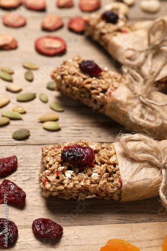 Tasty granola bars and ingredients on wooden table