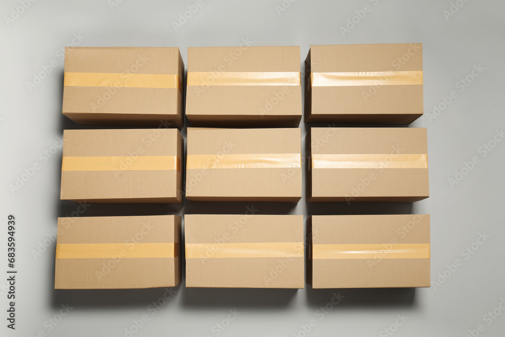 Many closed cardboard boxes with tape on light grey background, flat lay Many closed cardboard boxes with tape on light grey background, flat lay