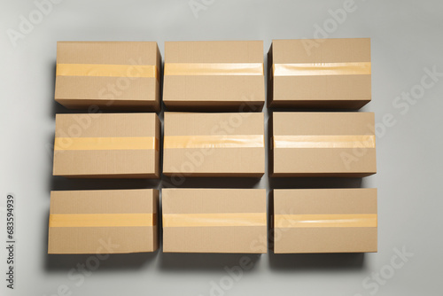 Many closed cardboard boxes with tape on light grey background, flat lay