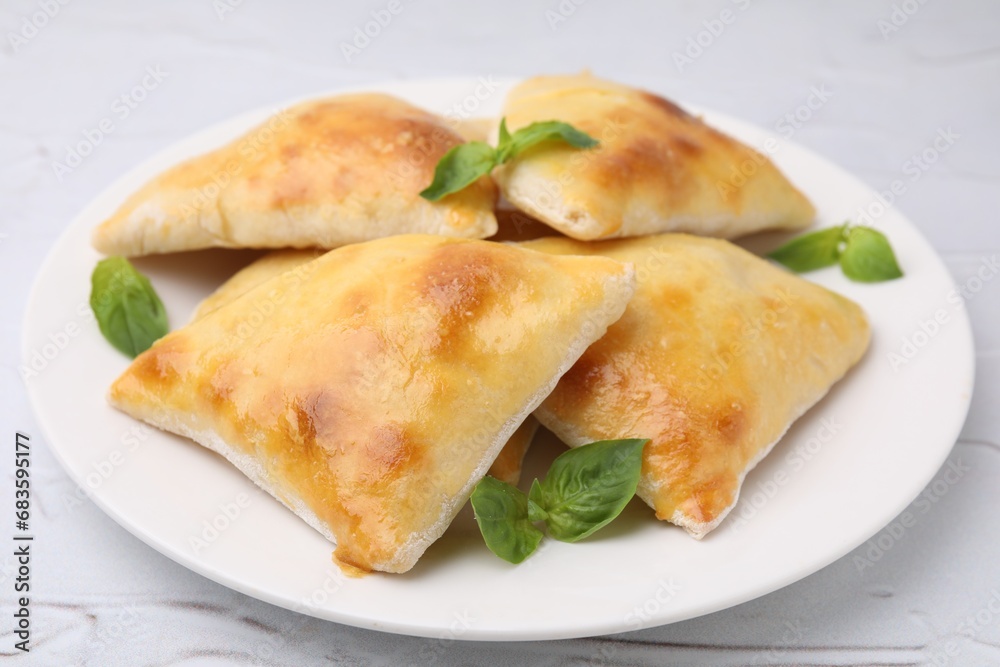 Delicious samosas and basil on white textured table, closeup Delicious samosas and basil on white textured table, closeup