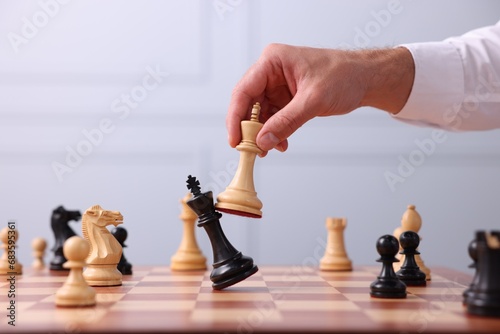 Man moving king chess piece at checkerboard indoors, closeup photo