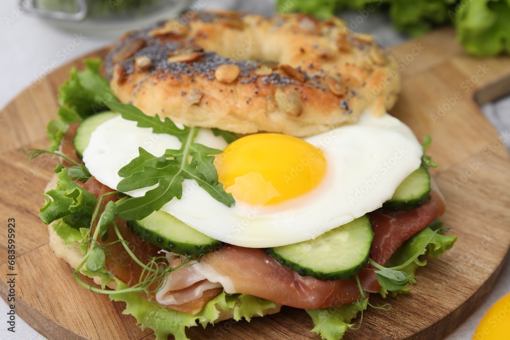 Tasty bagel with cured ham, egg, cucumber and salad mix on table, closeup Tasty bagel with cured ham, egg, cucumber and salad mix on table, closeup