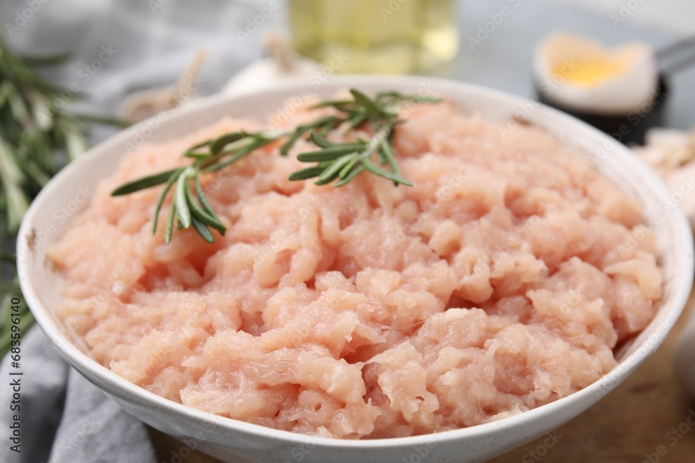 Fresh raw minced meat and rosemary in bowl on table, closeup Fresh raw minced meat and rosemary in bowl on table, closeup