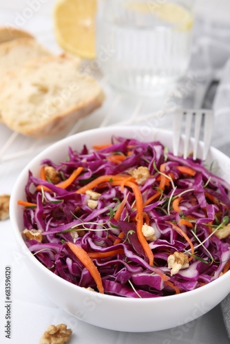 Tasty salad with red cabbage and walnuts on white table, closeup