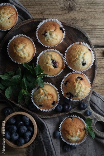 Delicious sweet muffins with blueberries and mint on wooden table, flat lay