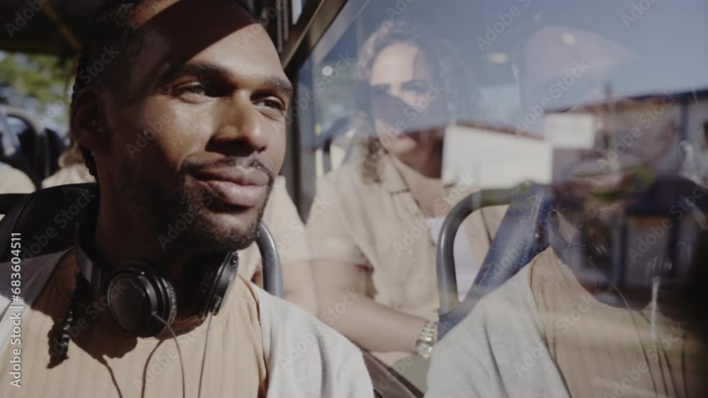 Young black man, with headphones, looking out the bus window. Cinematic 4k.