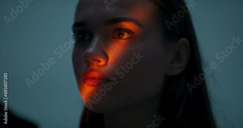 Beautiful unreal portrait fashion pretty girl with color lighting filters. Beauty girl face close up. Closeup woman with copy space standing isolated in front of light orange color.