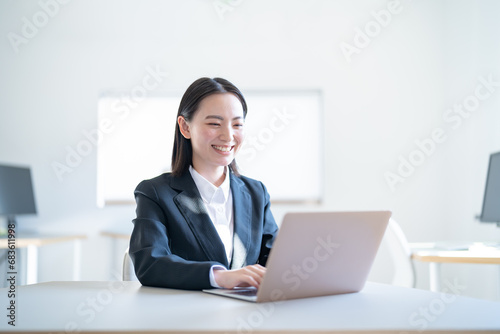 オフィスで仕事をするスーツを着た若い女性