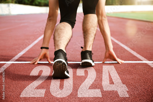 Rear view of a man preparing to start on an athletics track engraved with the year 2024.Happy New Year 2024.challenge, career path and change, readiness of leaders. Goals and plans for the next year. photo