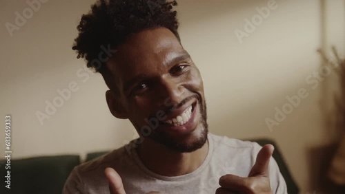 Homem negro sorridente sentado na cama fazendo sinal de postivo com os polegares. Cinematico 4k. photo