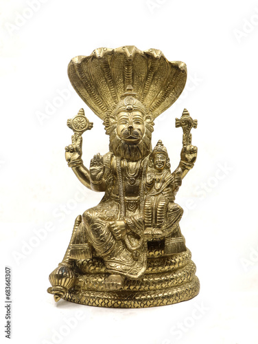 golden statue of lord vishnu avatar, narasimha lion faced with multiple hands sitting on a snake with multiple heads next to goddess lakshmi, front view isolated in a white background photo