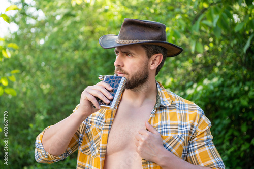man drink bourbon hipflask wear checkered shirt. photo of cowboy man drinking bourbon hipflask photo