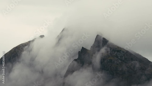Foggy clouds blowing over jagged mountain top in Iceland.