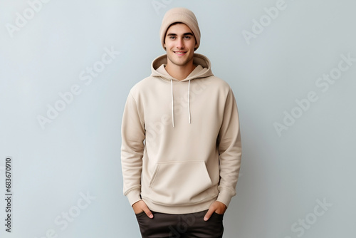 Male young model in beige blank hoodie on gray background. Clothes mockup. AI Generative