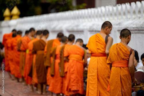 Buddhist alms giving ceremony in the early morning.Monks walk to collect alms and offerings.Sticky rice morning alms giving is held every day in Luang Prabang.Traditional ritual of alms giving in Laos photo