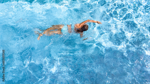 Active girl in swimming pool aerial drone view from above, young woman swims in blue water, tropical vacation, holiday on resort concept 