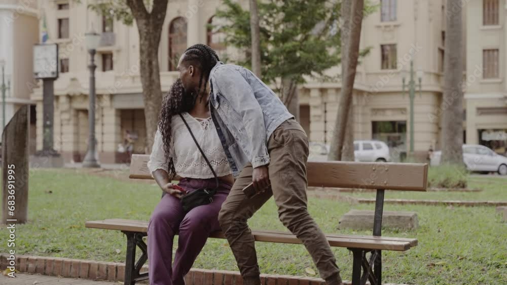 Young black friends, greeting with a kiss on the cheek, in the square on a sunny afternoon. Cinematic 4k. Young black friends, greeting with a kiss on the cheek, in the square on a sunny afternoon. Cinematic 4k.