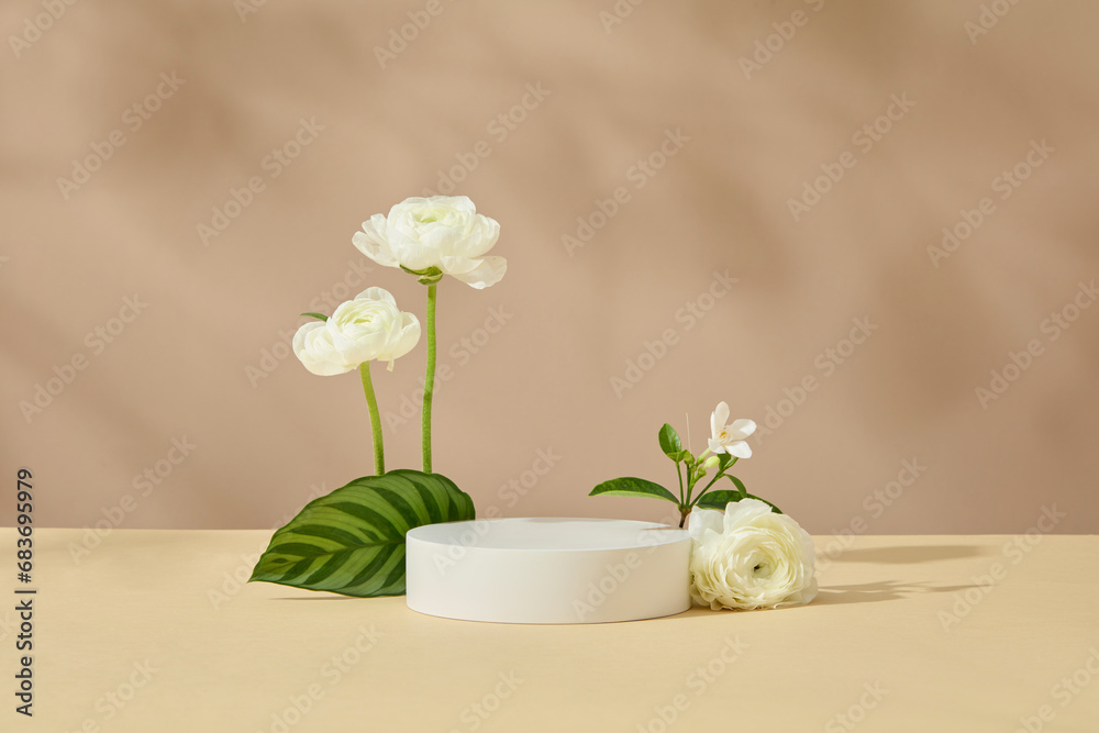 Pedestal for cosmetic product and packaging mockups presentation. Empty round podium decorated with beautiful white flower and green leaf on brown background. Front view Pedestal for cosmetic product and packaging mockups presentation. Empty round podium decorated with beautiful white flower and green leaf on brown background. Front view