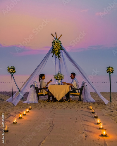 Romantic dinner on the beach in Phuket Thailand, couple man and woman mid age Asian woman and European man having dinner on the beach in Thailand during sunset.