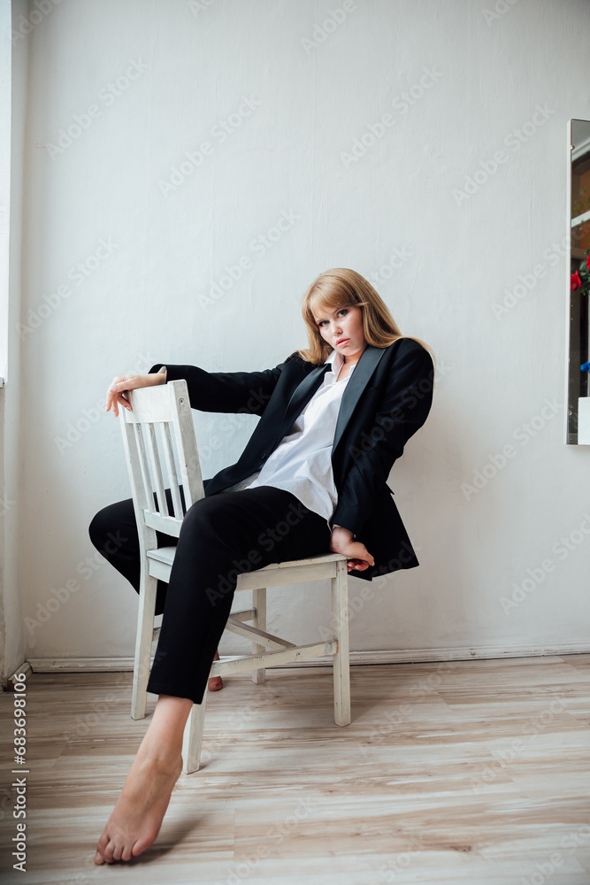 Beautiful young fashionable woman in black business suit sitting on a ...