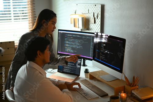 Male and female software developers sharing idea and discussing algorithms on computer screens