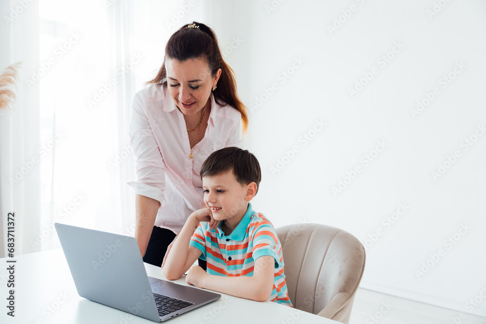 Woman teaching boy on laptop in school classroom Woman teaching boy on laptop in school classroom