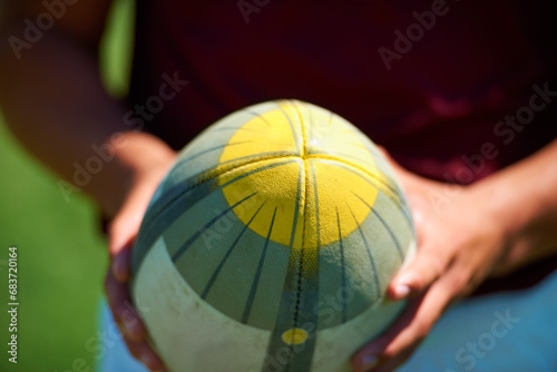 Hand, closeup and man holding a rugby ball for sports practice outdoors. Zoom, object and uniform with a male person training for a healthy active athlete competition or game on a field