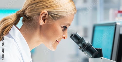 Professional female scientist is working on a vaccine in a modern scientific research laboratory. Laboratory tools: microscope, test tubes, equipment. Future technology, healthcare and science.