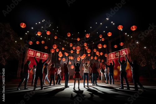 A group of people in a dark night square release glowing red Chinese lanterns to fly into the sky. Happy Chinese New Year celebration.