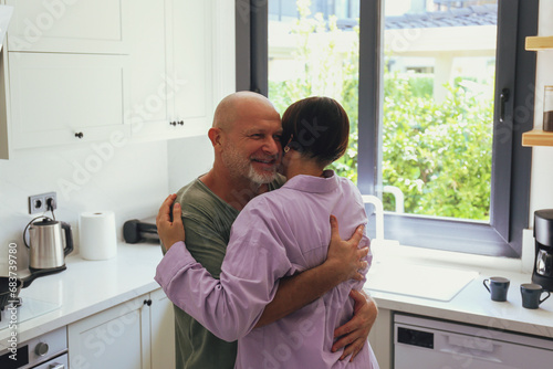 Mid adult couple dancing in the kitchen, expressing their love to each other through physical affection. Close up, copy space, interior background.