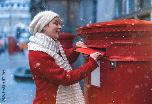 woman in a red coat  putting a card in the red postbox and walking around an English city on a snowy day
