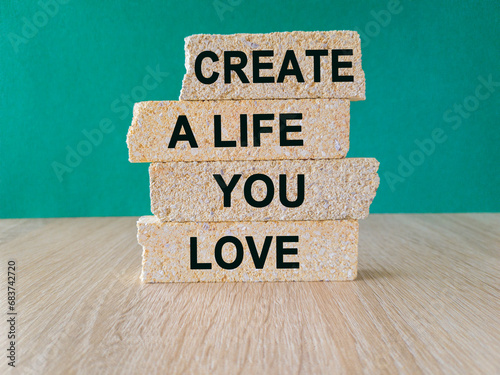 Motivational quote Create a life you love written on brick block. Beautiful wooden table green background. Business concept. Copy space. photo