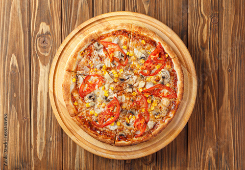 delicious pizza with chicken, mushrooms, cheese, tomatoes and corn on a wooden background