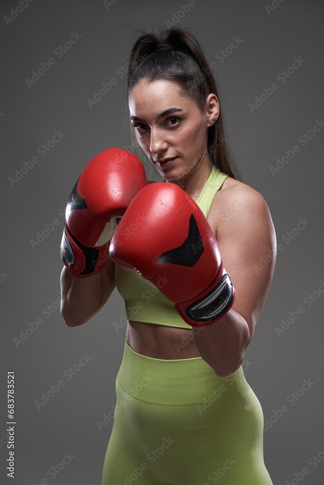 Woman boxer with red gloves isolated on gray background Woman boxer with red gloves isolated on gray background