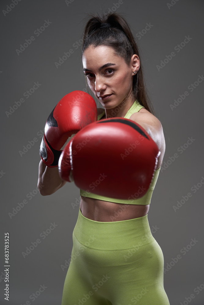 Woman boxer with red gloves isolated on gray background Woman boxer with red gloves isolated on gray background