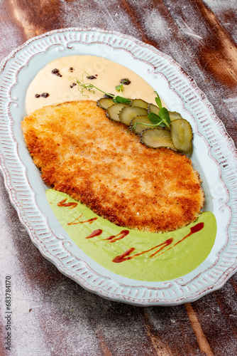 Viennese chicken schnitzel with sauces and pickles. Haute cuisine. On a wooden background.