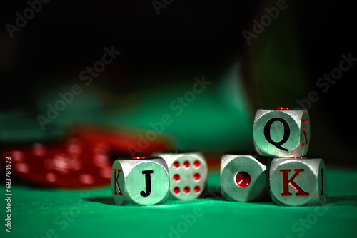 Cubilete con dados de póker descansando sobre un tapete verde con fichas rojas. Enfoque selectivo. photo