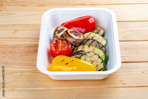 Grilled vegetables. Healthy diet. Takeaway food. Eco packaging. On a wooden background.